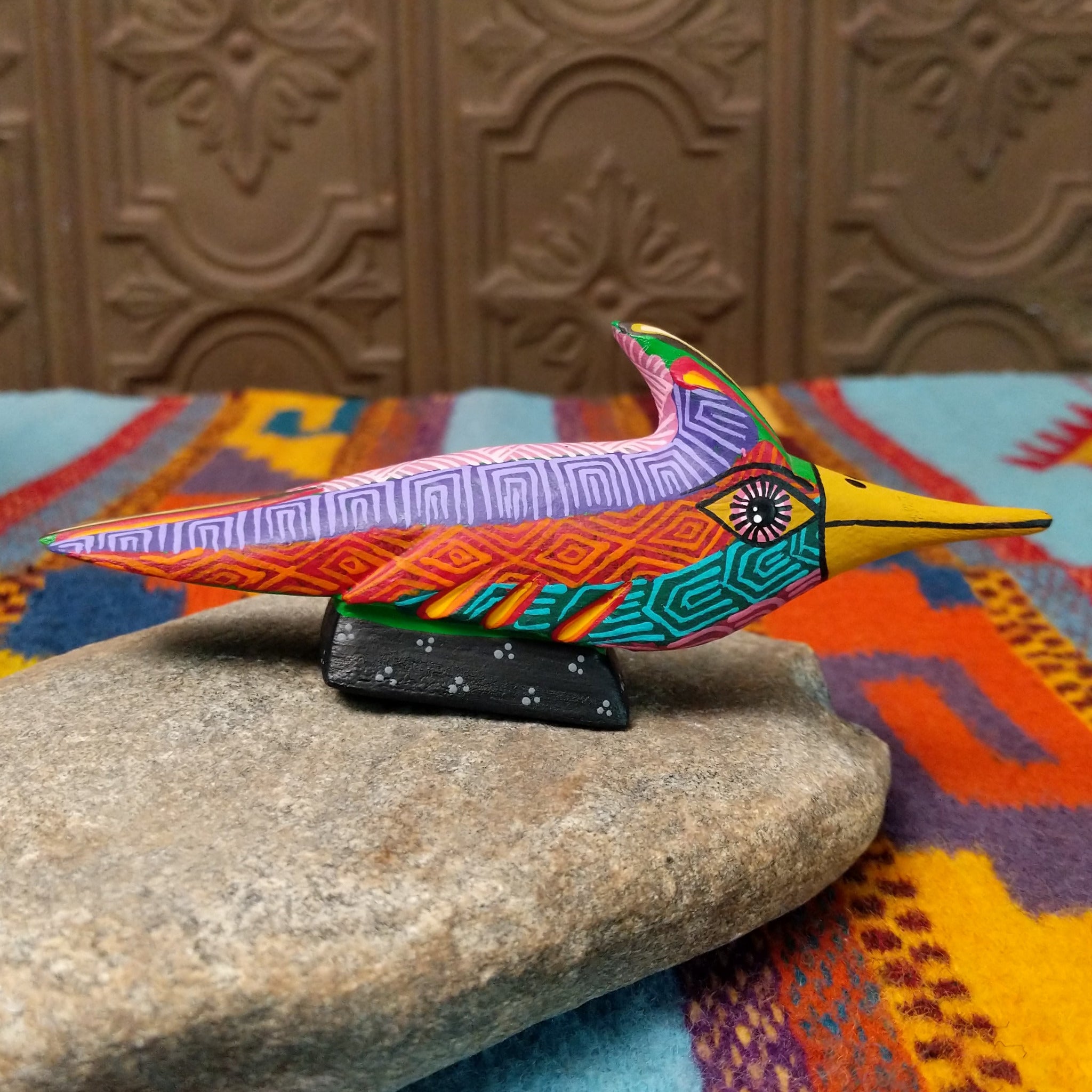 Oaxacan roadrunner wood carving by Julia Calvo Olivera with a long yellow beak, swept-back crest, and multicolored geometric patterns.