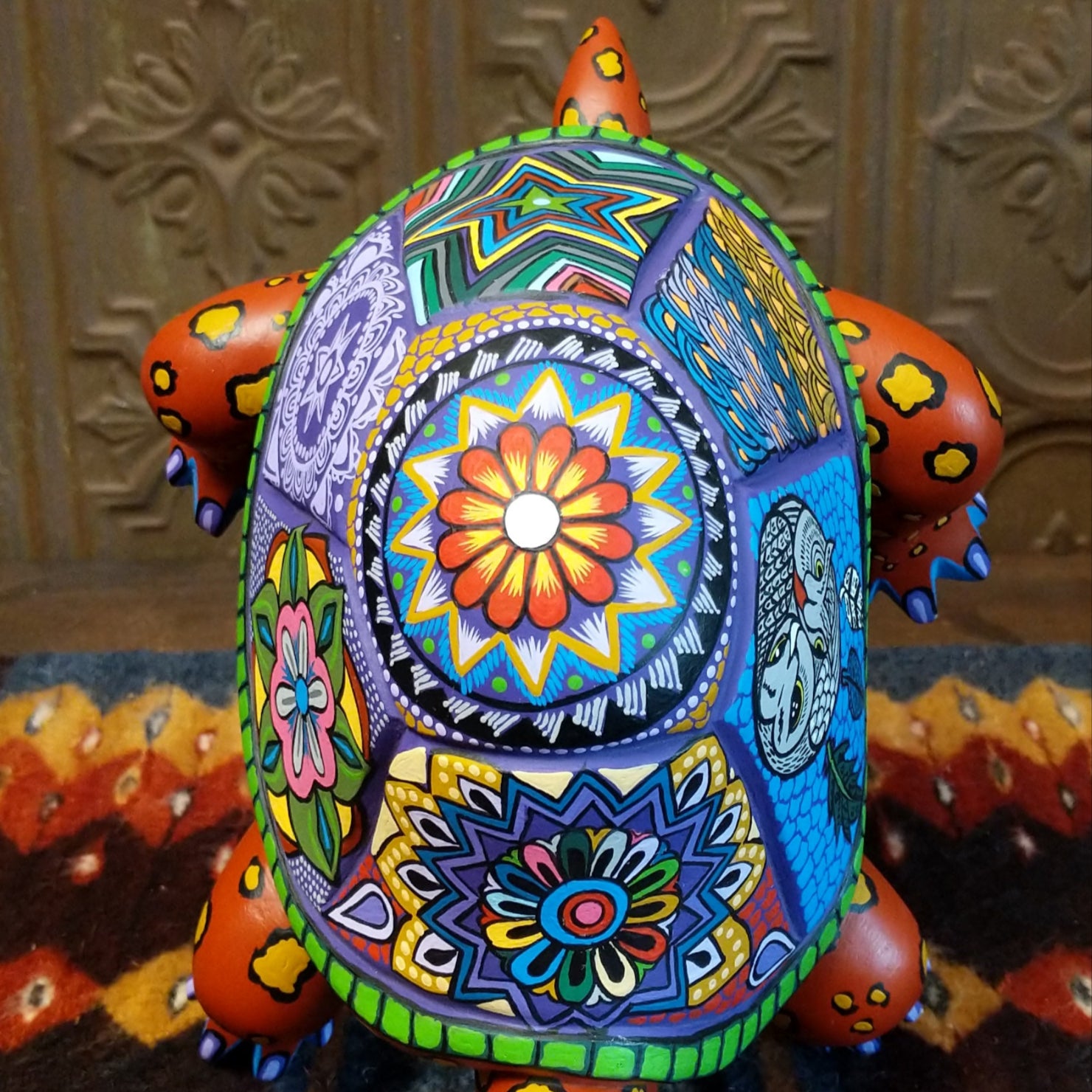 Floral motifs on the orange wood shell, with fine yellow and blue accents.