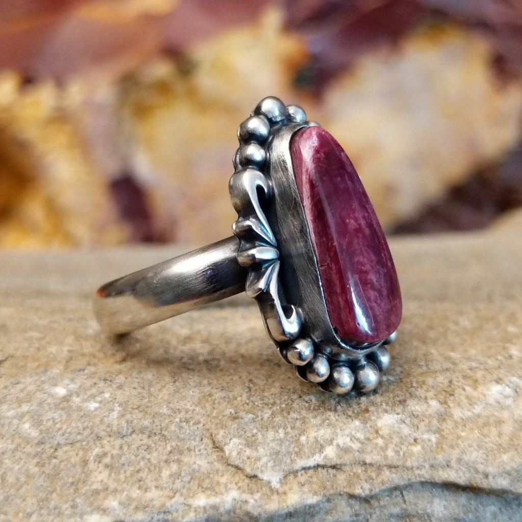 Oblong spiny oyster shell set in an sterling silver bezel with dotted accents and ornate silver-work.