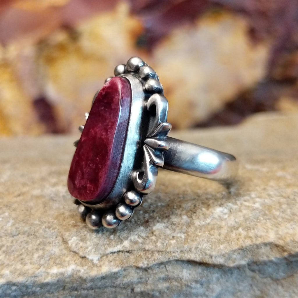 Oblong spiny oyster shell set in an sterling silver bezel with dotted accents and ornate silver-work.