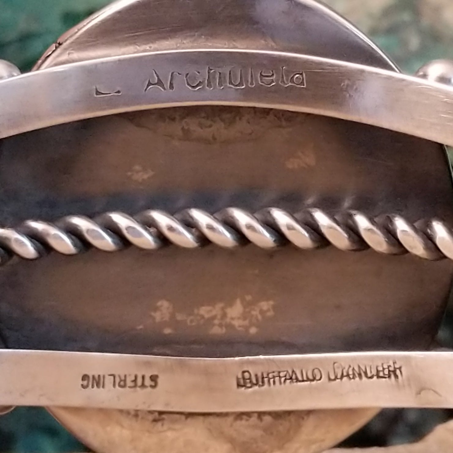 The signature is etched on the inner sterling silver band of the cuff.