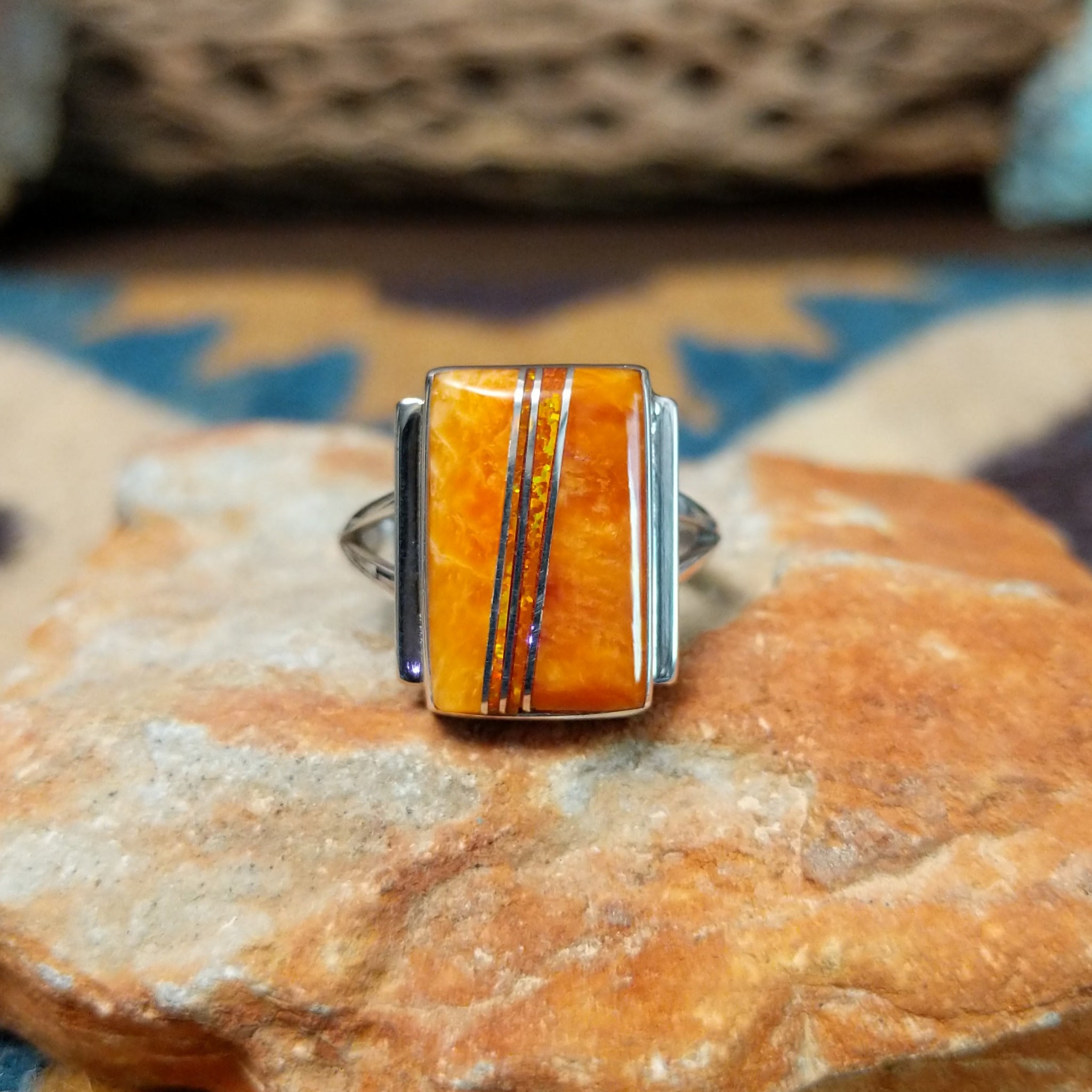 Handcrafted sterling silver orange spiny oyster and manmade opal ring by Sheryl Martinez, featuring a rectangular inlay with shimmering opal accents.