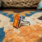 Handcrafted sterling silver orange spiny oyster and manmade opal ring by Sheryl Martinez, featuring a rectangular inlay with shimmering opal accents; side view.