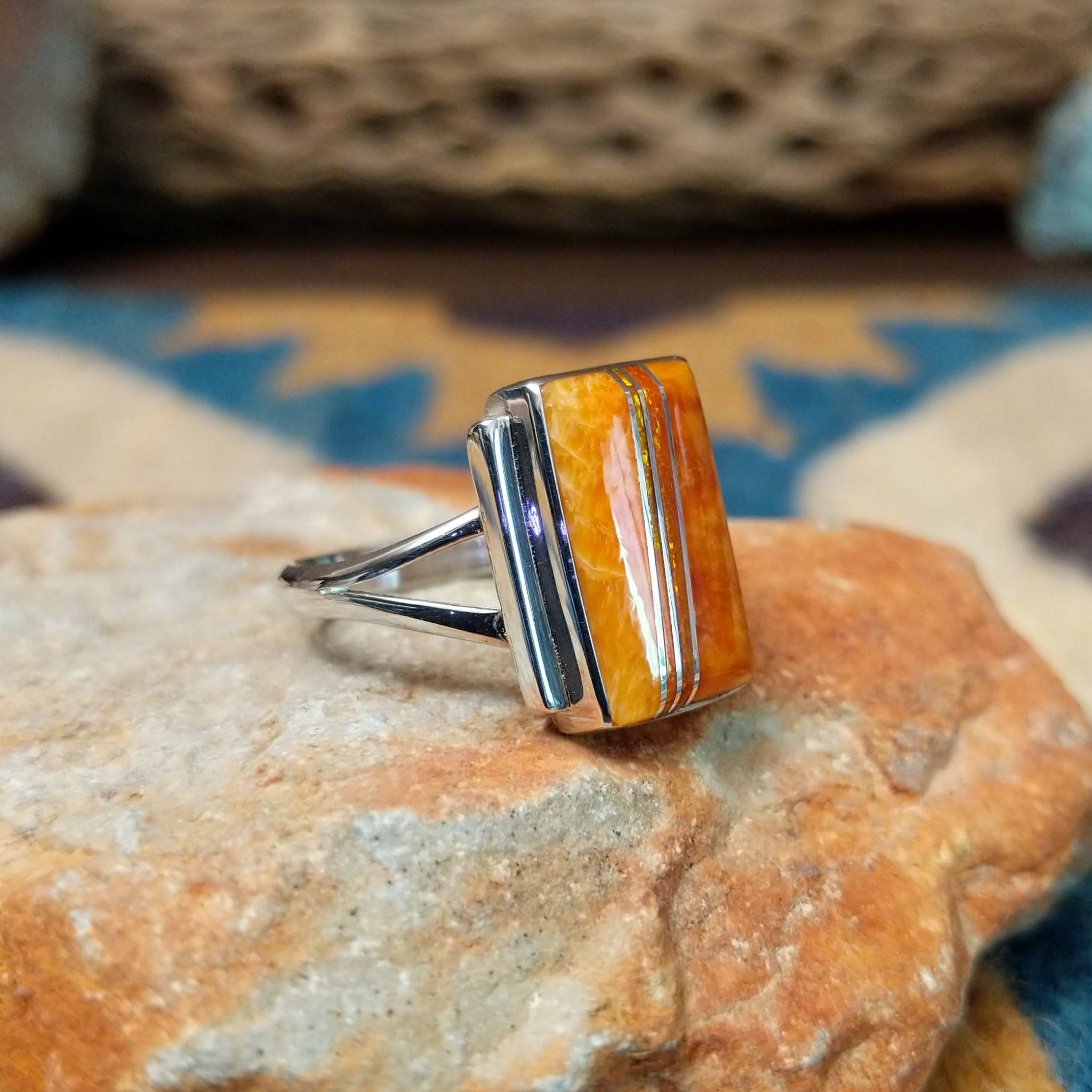 Handcrafted sterling silver orange spiny oyster and manmade opal ring by Sheryl Martinez, featuring a rectangular inlay with shimmering opal accents; side view.