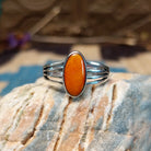 Sterling silver ring with orange spiny oyster shell set in an oval bezel and layered band.