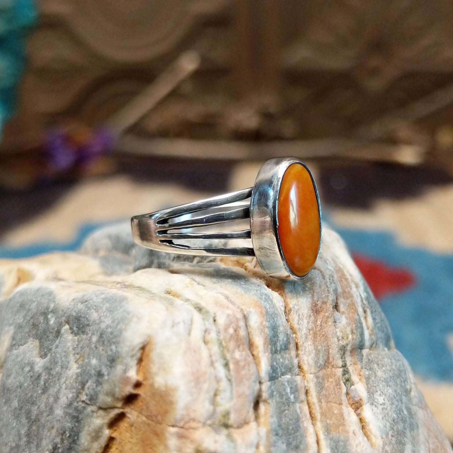 Sterling silver ring with orange spiny oyster shell set in an oval bezel and layered band.