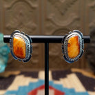 Sterling silver earrings featuring orange spiny oyster shell set in bezels, framed by twisted rope and etched setting.