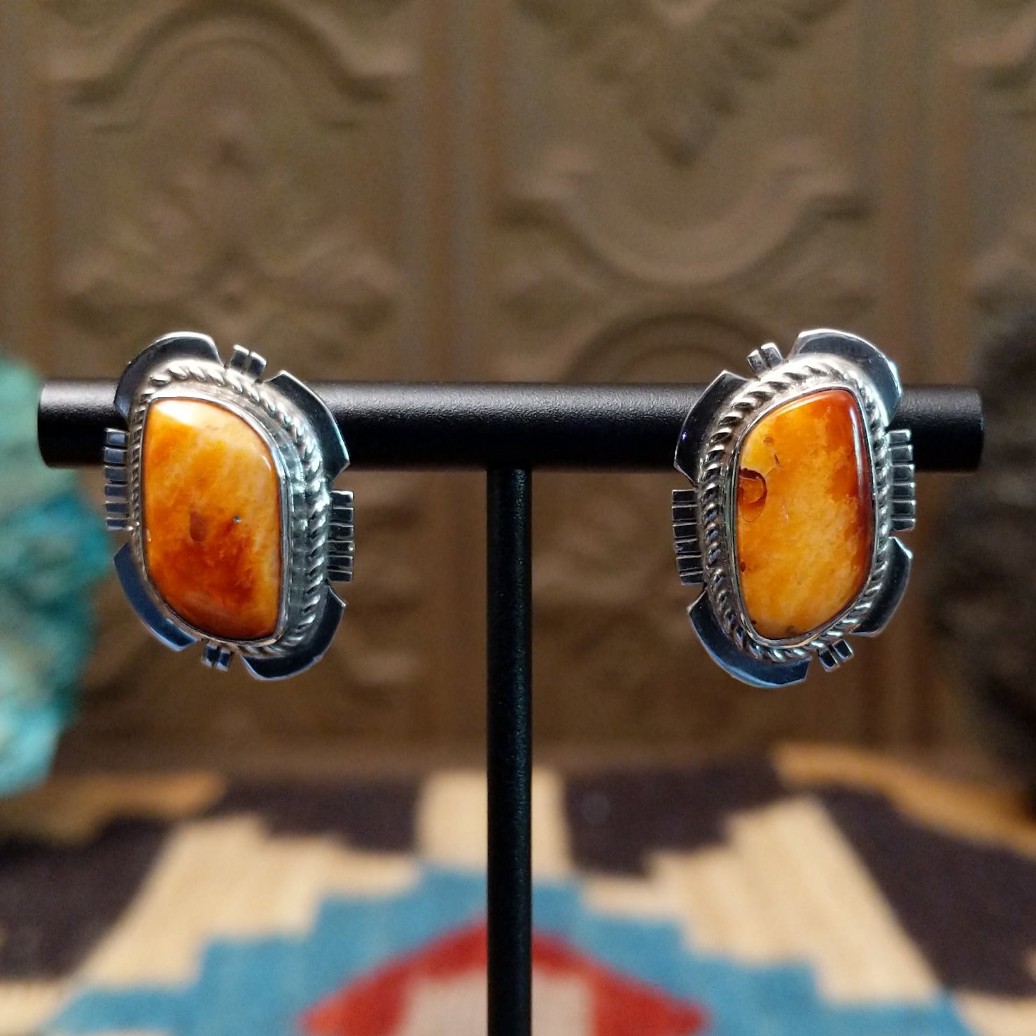 Sterling silver earrings featuring orange spiny oyster shell set in bezels, framed by twisted rope and etched setting.