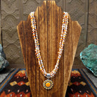 Features multi-strand orange spiny oyster shell heishi beads with white beads and pendant.