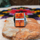Orange spiny oyster shell inlay ring by Raymond Coriz with a central opal strip and rectangular silver setting.