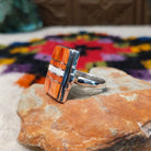 Orange spiny oyster shell inlay ring by Raymond Coriz with a central opal strip and rectangular silver setting.