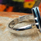 Orange spiny oyster shell inlay ring by Raymond Coriz with a central opal strip and rectangular silver setting. Close up of the artist's stamped signature.
