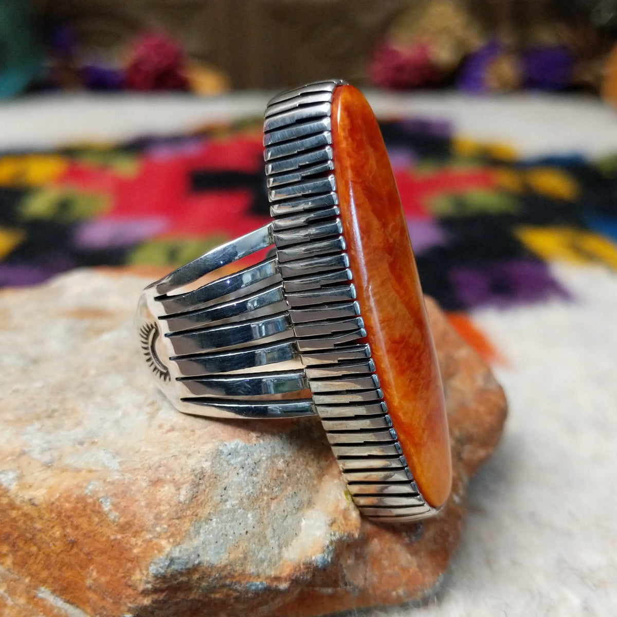 Orange Spiny Oyster Shell Navette Ring by Bernyse Chavez with an elongated orange and red shell cabochon, detailed sterling silver bezel, and wide split-style band; side view.