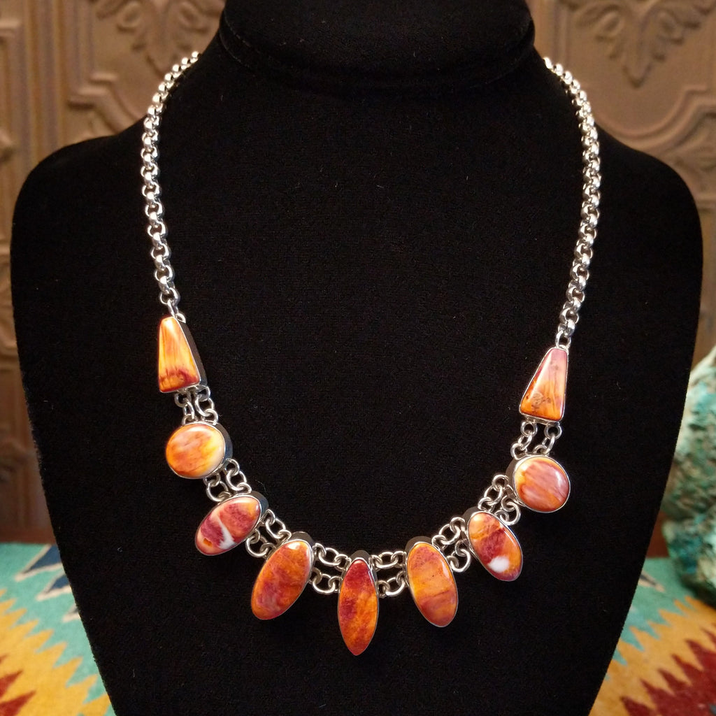 Orange spiny oyster shell set in various shaped bezels on a sterling silver chain.