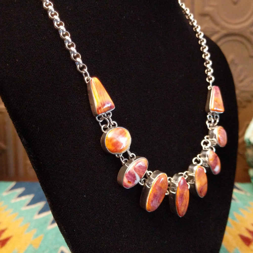 Orange spiny oyster shell set in various shaped bezels on a sterling silver chain.
