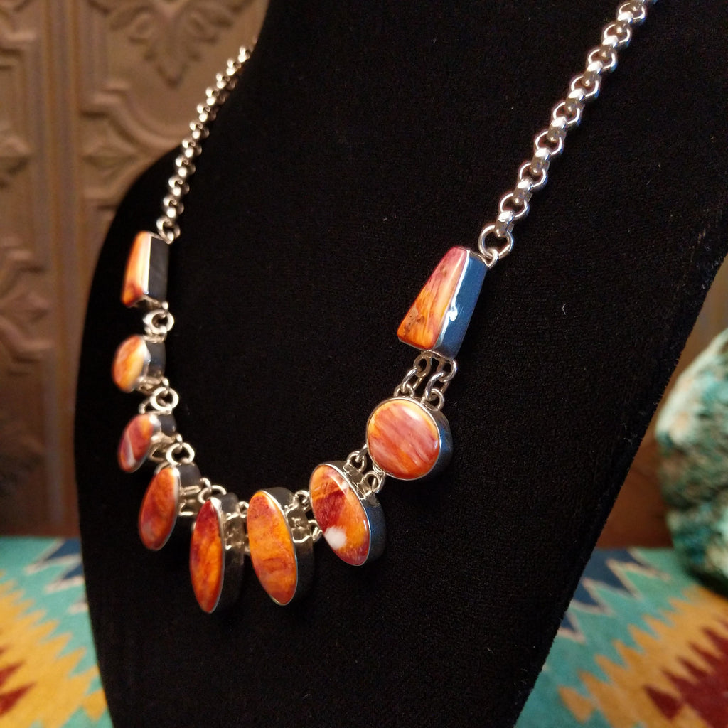 Orange spiny oyster shell set in various shaped bezels on a sterling silver chain.