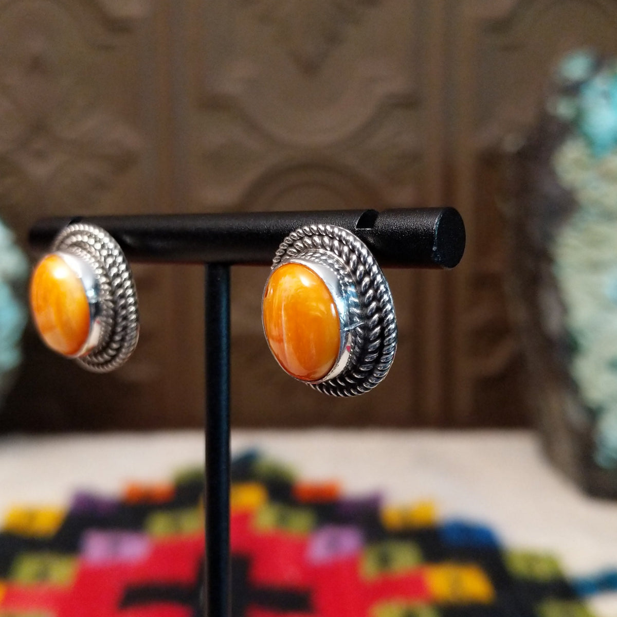 Orange Spiny Oyster Shell Oval Earrings by Priscilla Smith featuring vivid orange oval shell cabochons with natural golden variations, set in silver with layered twisted rope-style borders; side view.