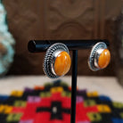 Orange Spiny Oyster Shell Oval Earrings by Priscilla Smith featuring vivid orange oval shell cabochons with natural golden variations, set in silver with layered twisted rope-style borders; side view.