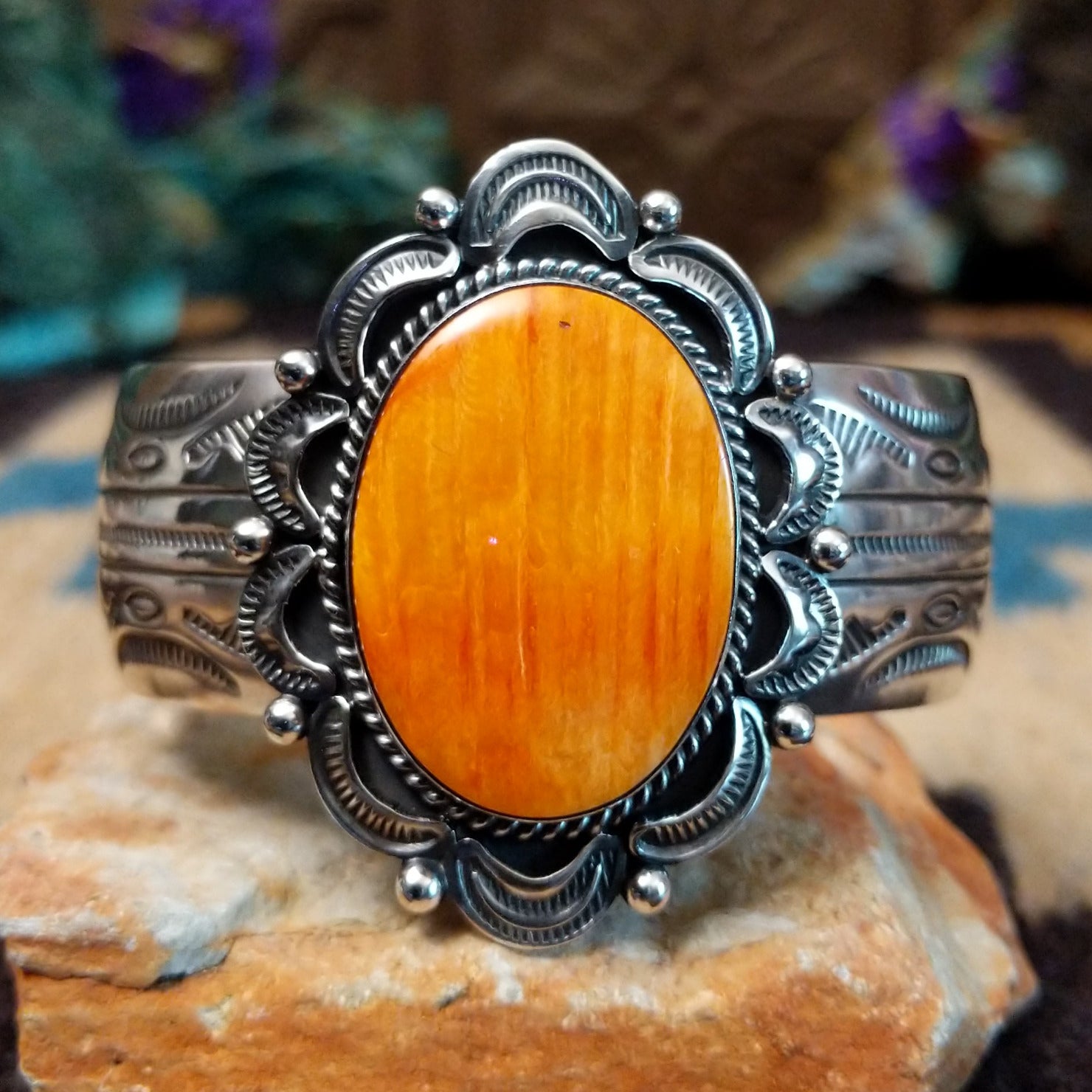 Orange spiny oyster shell portrait cuff by Philbert Secatero and Raymond Coriz, featuring a detailed shell portrait set in handcrafted Southwestern-inspired metalwork.