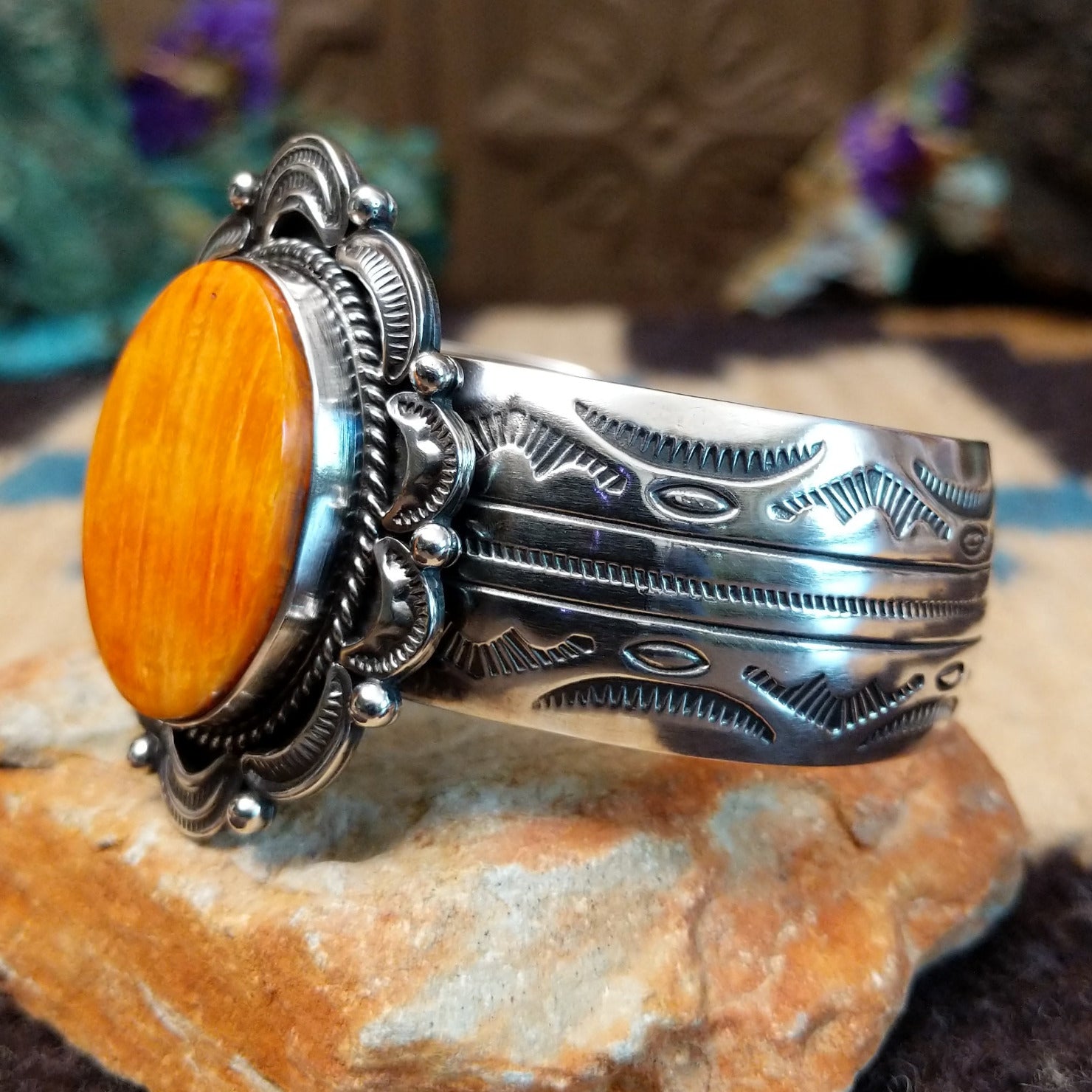 Orange spiny oyster shell portrait cuff by Philbert Secatero and Raymond Coriz, featuring a detailed shell portrait set in handcrafted Southwestern-inspired metalwork.  Side view.