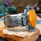 Orange spiny oyster shell portrait cuff by Philbert Secatero and Raymond Coriz, featuring a detailed shell portrait set in handcrafted Southwestern-inspired metalwork.  Side view.