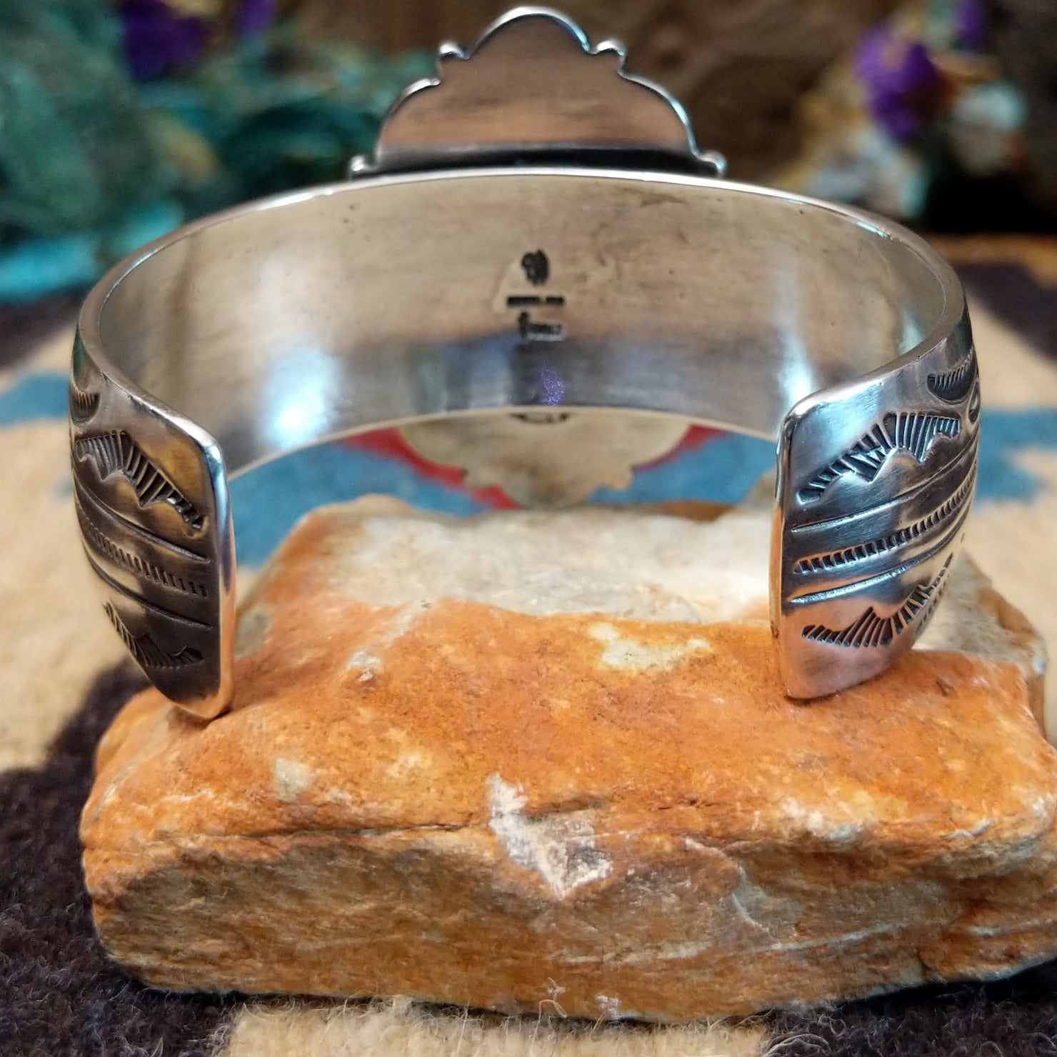 Orange spiny oyster shell portrait cuff by Philbert Secatero and Raymond Coriz, featuring a detailed shell portrait set in handcrafted Southwestern-inspired metalwork.  Underside view.