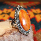 Sterling silver ring with oval orange spiny oyster shell set in the bezel, framed by twisted rope and dotted accents.