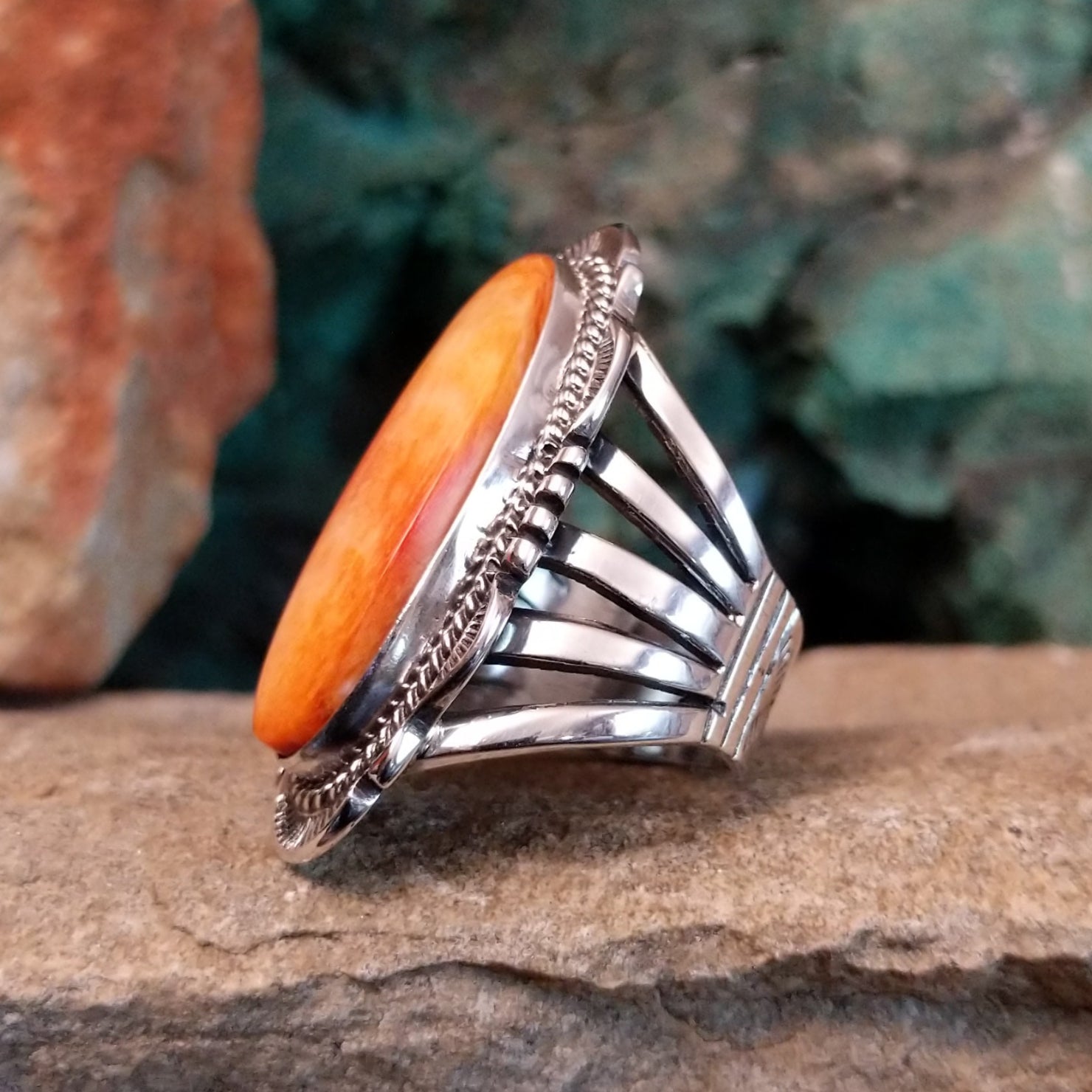 The side of the ring shows the smooth bezel with the orange spiny oyster shell, accented by twisted silver rope along the band.