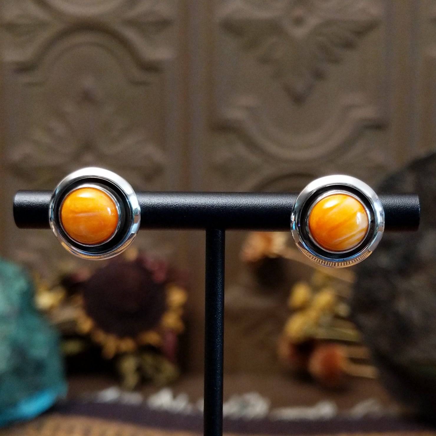 Sterling silver stud earrings featuring round orange spiny oyster shell stones in polished bezel settings.