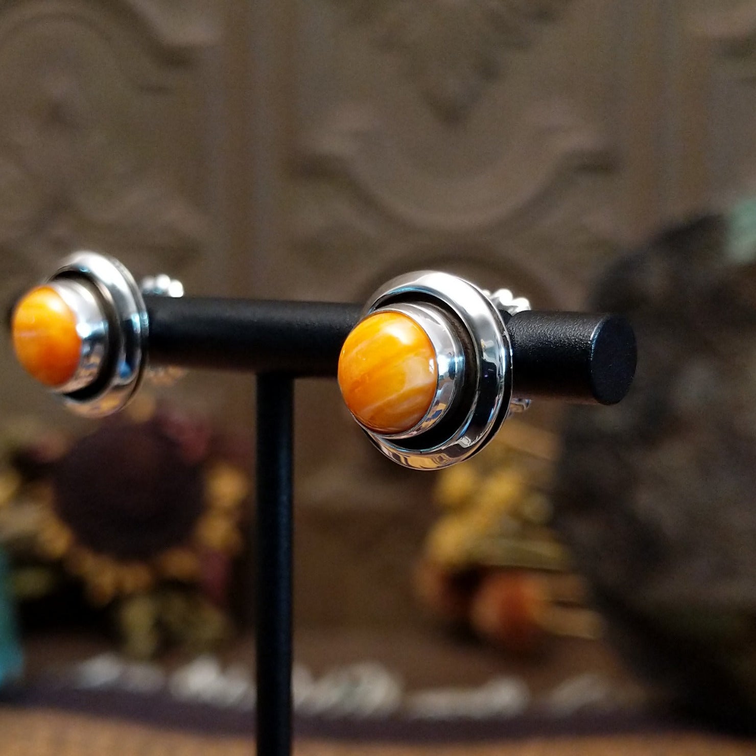 Sterling silver stud earrings featuring round orange spiny oyster shell stones in polished bezel settings.