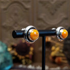 Sterling silver stud earrings featuring round orange spiny oyster shell stones in polished bezel settings.