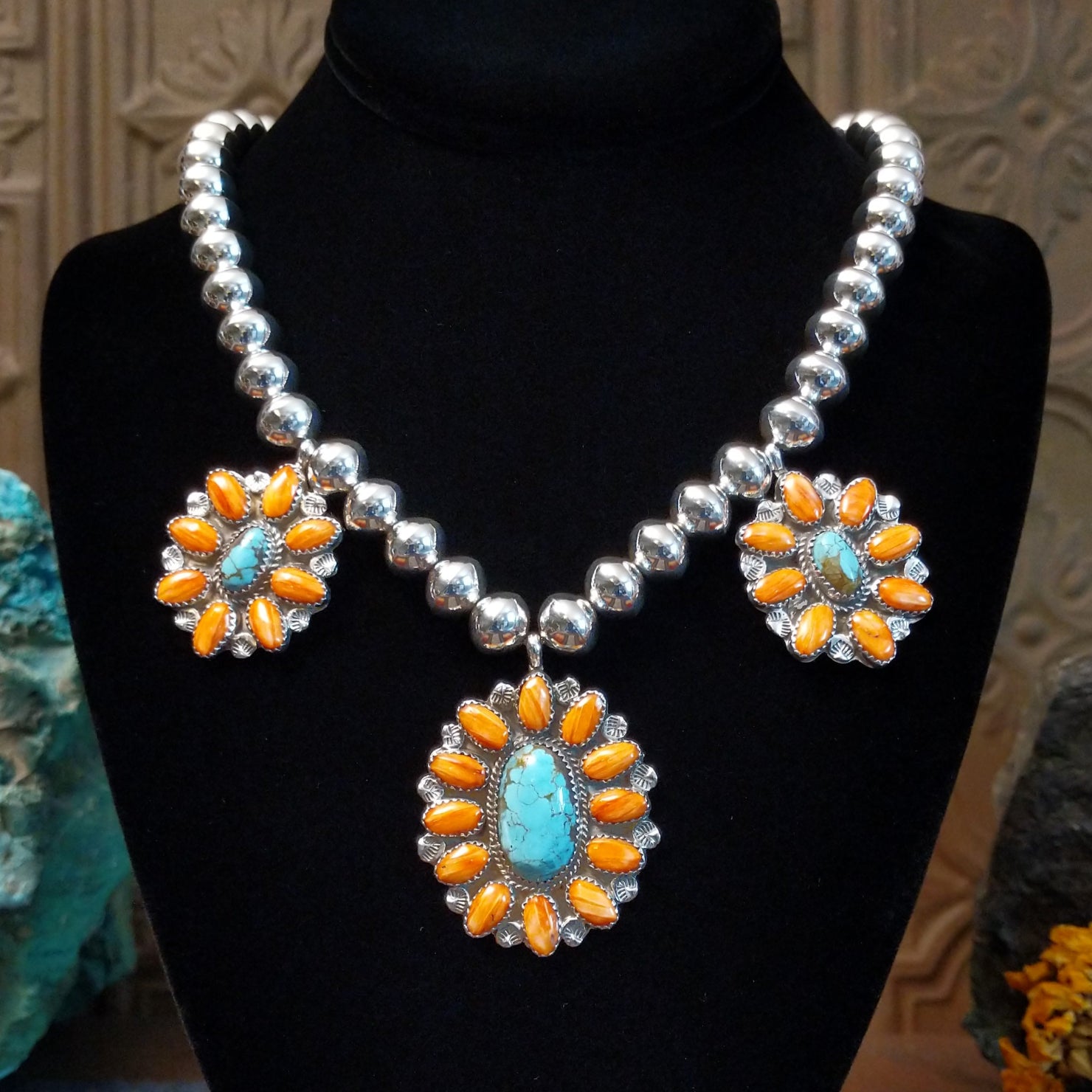 The necklace has a sterling silver beaded chain with three cluster pendants, each with turquoise and orange spiny oyster shell on the bezels with twisted silver rope detailing.