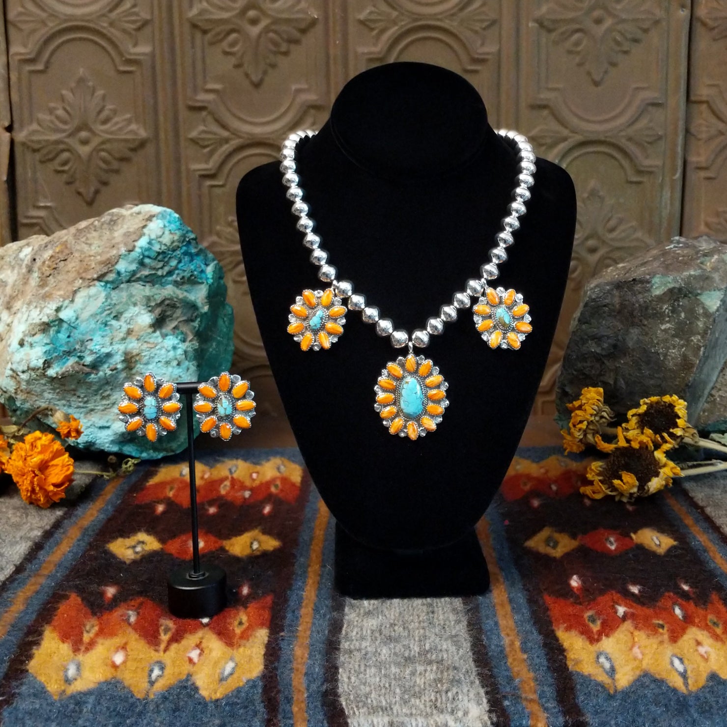 A sterling silver necklace and earrings set with turquoise stones and orange spiny oyster shell set on bezels on both the beaded chain and post earrings.