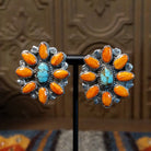 The earrings feature a cluster of orange spiny oyster shell pieces around a turquoise stone in a bezel with twisted silver rope.