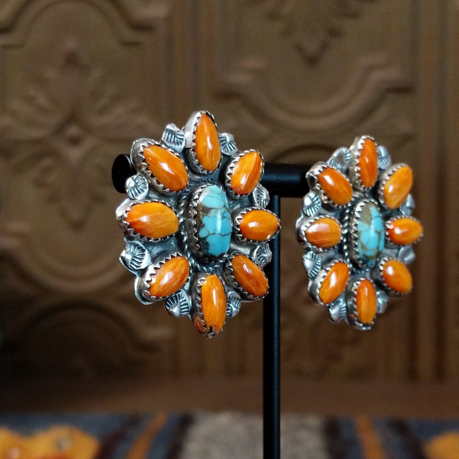 The partial side angle displays the turquoise stone and orange spiny oyster shell on the bezel of the earrings.