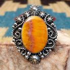 Sterling silver ring with orange spiny oyster shell set in the bezel, framed by ornate silverwork.