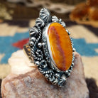 Sterling silver ring with orange spiny oyster shell set in the bezel, framed by ornate silverwork.