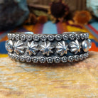 Wide silver cuff by Marc Antia with raised silver ornaments, fluted details, and beaded borders.