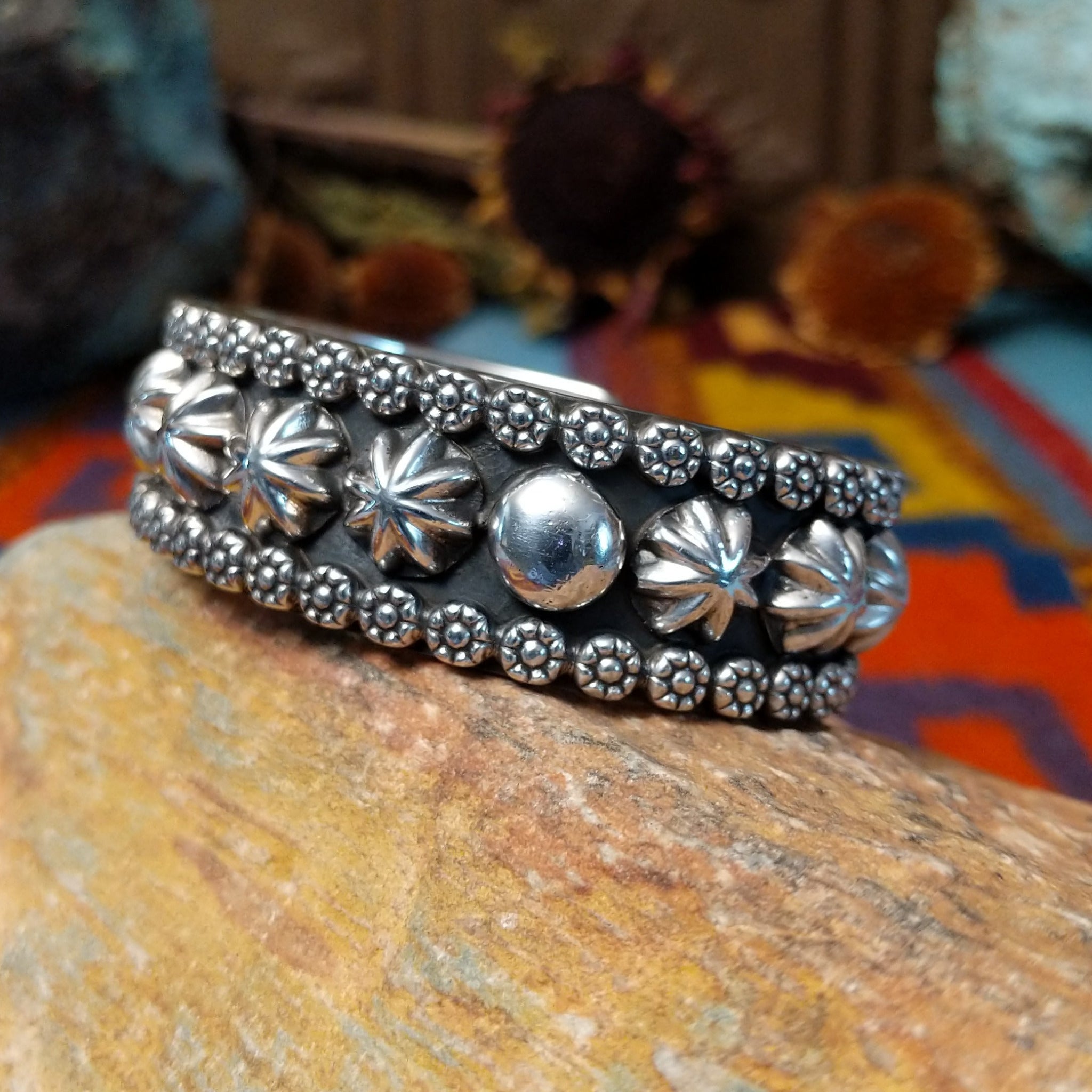 Wide silver cuff by Marc Antia with raised silver ornaments, fluted details, and beaded borders.
