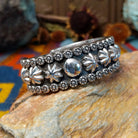 Wide silver cuff by Marc Antia with raised silver ornaments, fluted details, and beaded borders.