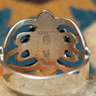 Handcrafted Navajo sterling silver ring by Raymond Coriz featuring an oval red coral cabochon surrounded by twisted rope, silver bead accents, and an ornate openwork floral design; artisan and Sterling Silver stamp.