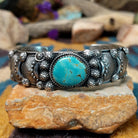 Handcrafted sterling silver cuff by Andrew Gordon featuring a Kingman turquoise cabochon with a twisted rope bezel, surrounded by ornate conchos, fan motifs, silver beadwork, and hand-stamped Southwestern details.