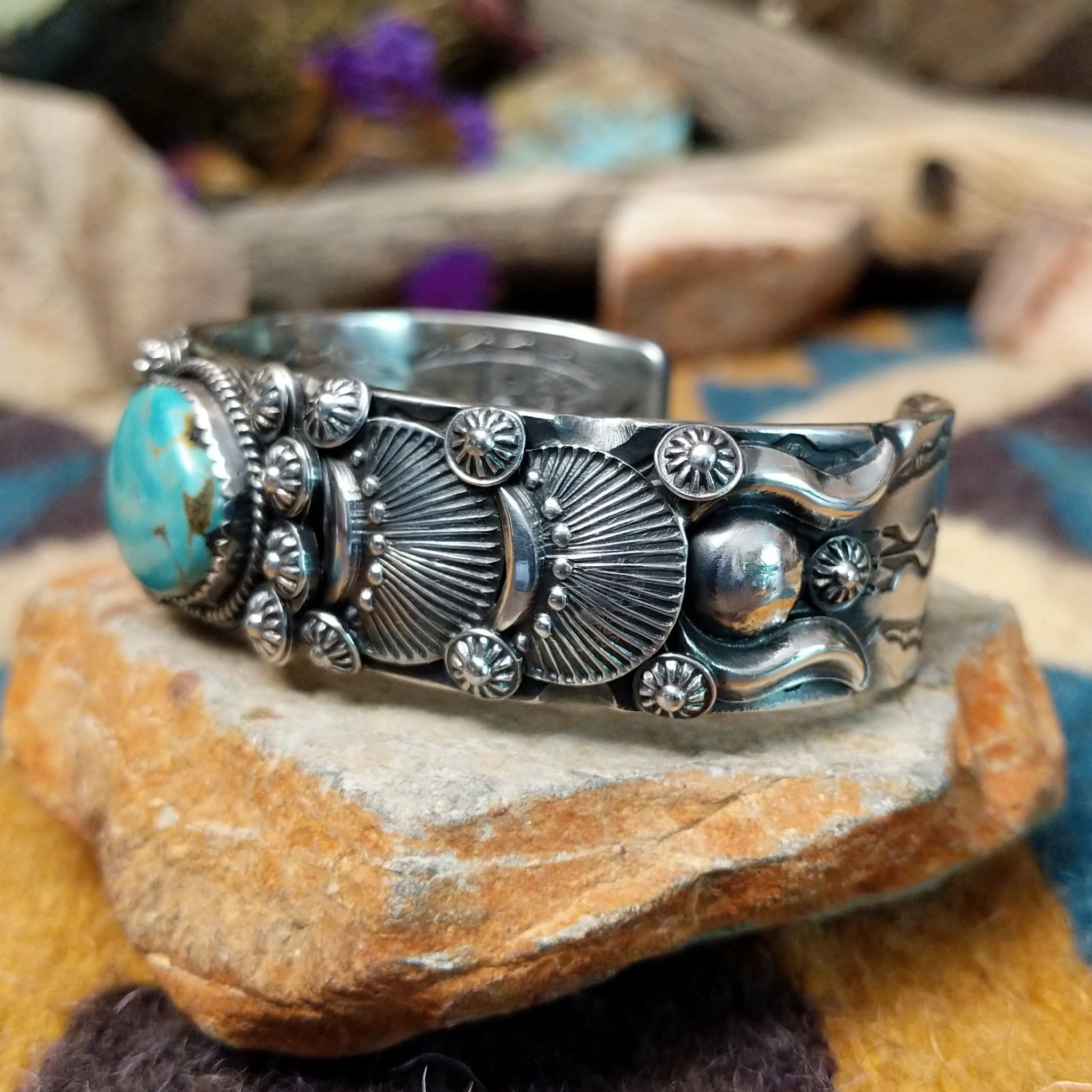 Handcrafted sterling silver cuff by Andrew Gordon featuring a Kingman turquoise cabochon with a twisted rope bezel, surrounded by ornate conchos, fan motifs, silver beadwork, and hand-stamped Southwestern details; side view.