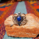 Ornate Lapis Ring by Raymond Coriz featuring an oval blue lapis stone set in Sterling Silver with twisted rope, polished bead accents, sculpted details, and decorative openwork.