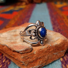 Ornate Lapis Ring by Raymond Coriz featuring an oval blue lapis stone set in Sterling Silver with twisted rope, polished bead accents, sculpted details, and decorative openwork; side view.