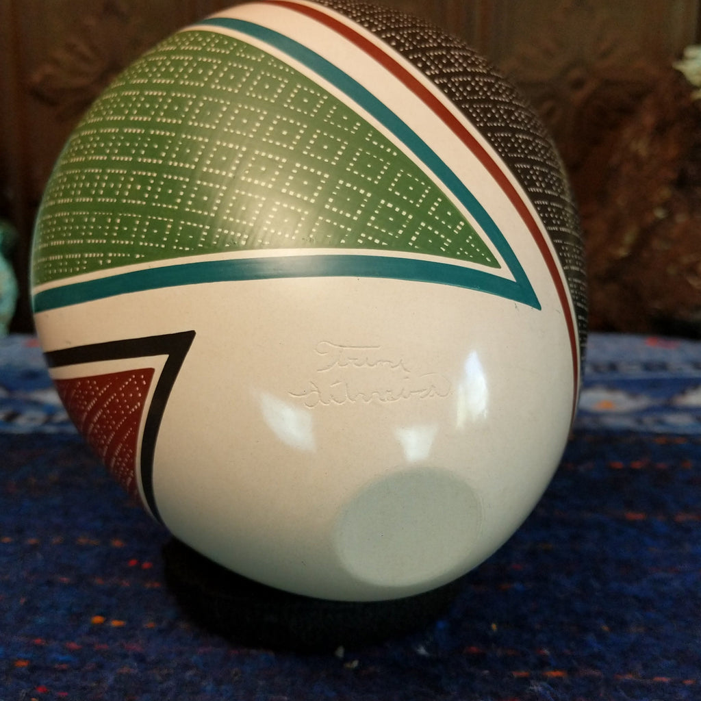 The base of the glazed pot is etched with the artisan's signature.