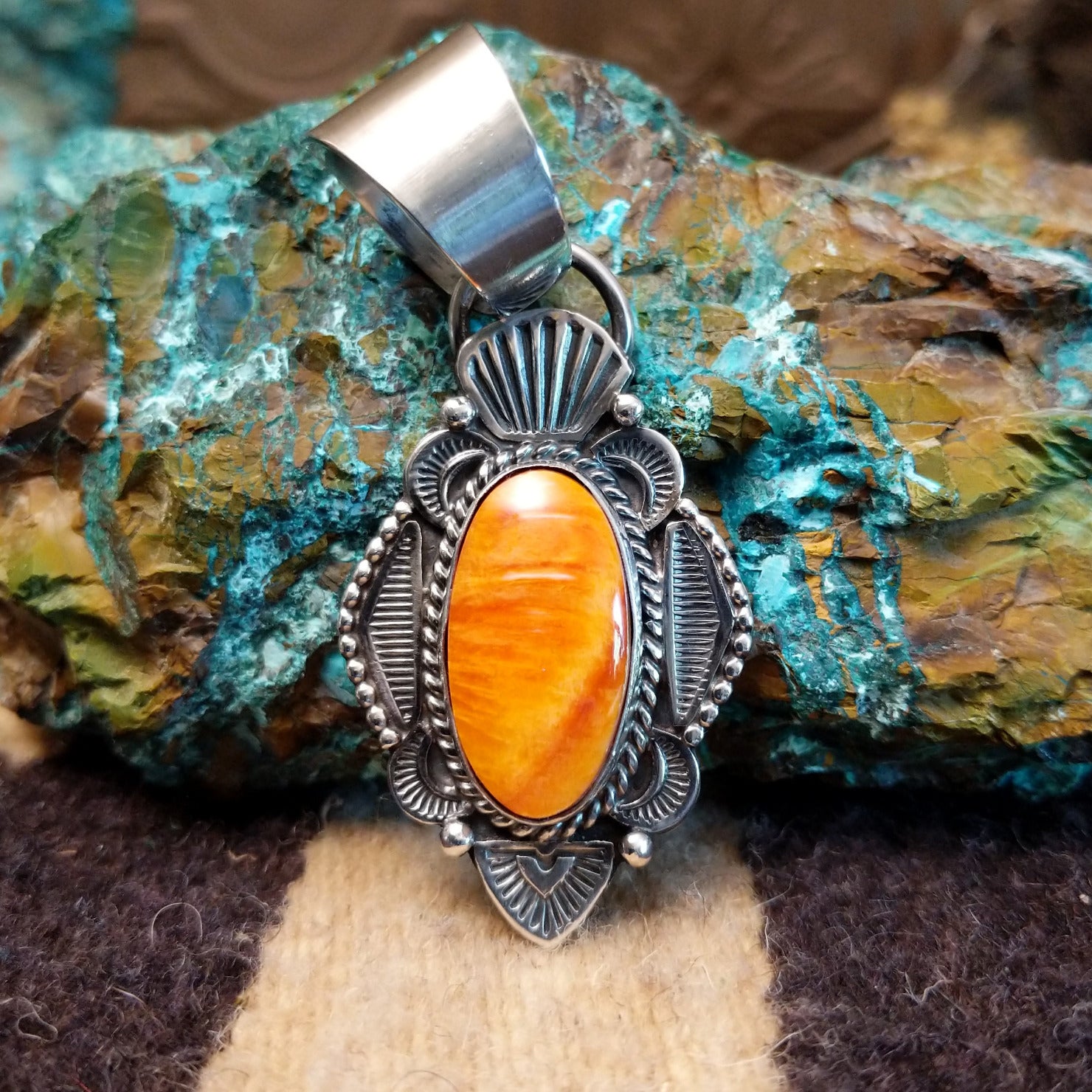 Sterling silver pendant with orange spiny oyster shell set in an oval bezel, framed by ornate silverwork.