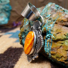 Sterling silver pendant with orange spiny oyster shell set in an oval bezel, framed by ornate silverwork.
