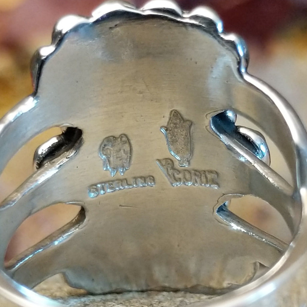 The artisan's signature is stamped on the underside of the setting.