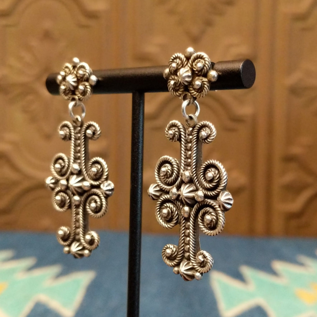 Ornate sterling silver cross earrings with floral detailing and dot work.